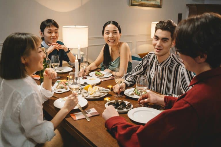 A group of five friends are having dinner together. They are talking and laughing together.